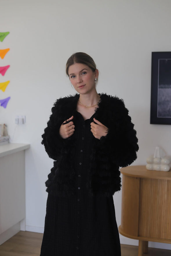 The Drama the Label Fur Baby Jacket is a must-have for every wardrobe. This super fluffy and dramatic black jacket features three hook and eye closures and is fully lined. It is the perfect choice for chilly nights out or for a more casual day look. With its luxurious fur look and impeccable design, this jacket adds a touch of elegance to any outfit. Its soft and cozy texture will keep you warm and stylish throughout the colder seasons.
