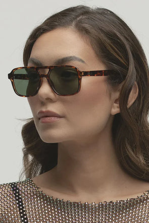Bringing a modern twist to a '70s classic, the Kiki sunglasses from Otra offer an upgraded take on the traditional flat tops. These shades sport a rounded aviator shape and full framing, offering a contemporary spin. With a sturdy brow and gracefully curved edges, the Kiki is a medium fit, becoming a go-to choice for those seeking timeless style with a fresh twist.