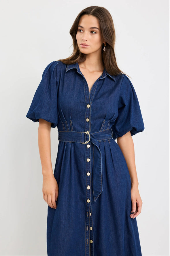 Dark indigo denim dress with a structured silhouette

Button-down front and panel seam detailing

D-ring belt for an adjustable, flattering fit

Soft puff sleeves with gentle volume

80% Cotton, 20% Polyester – durable yet comfortable

Style it casual or elevated for endless versatility