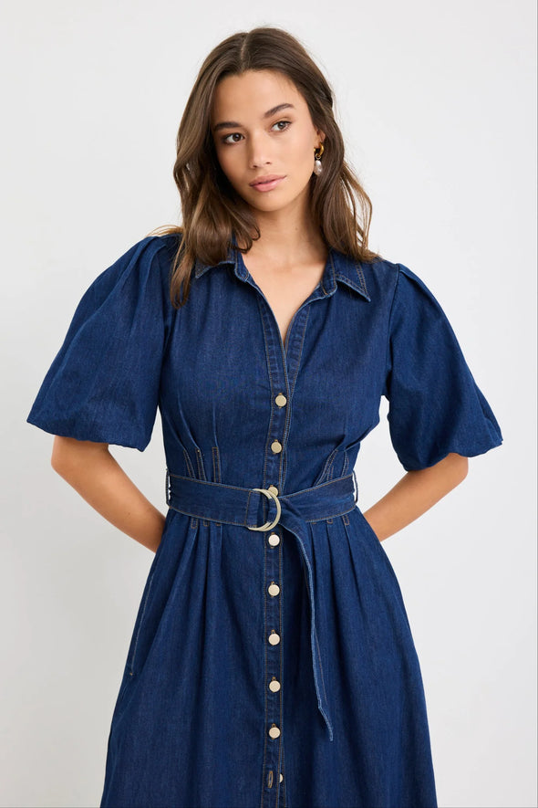 Dark indigo denim dress with a structured silhouette

Button-down front and panel seam detailing

D-ring belt for an adjustable, flattering fit

Soft puff sleeves with gentle volume

80% Cotton, 20% Polyester – durable yet comfortable

Style it casual or elevated for endless versatility