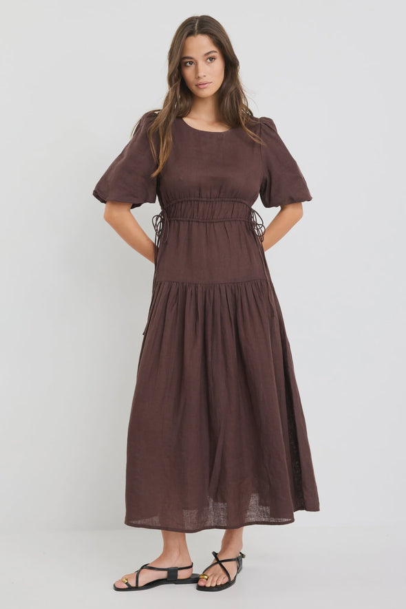 100% linen for breathable, natural comfort

Puff sleeves with soft volume for a feminine touch

Adjustable waist ties for a custom fit

Tiered skirt adds movement and flow

Midi length for timeless, versatile styling

Chocolate brown hue for an elegant, earthy look

Perfect for both casual wear and dressier occasions