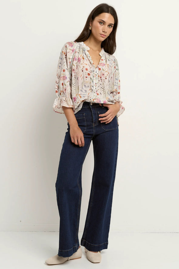 Add a playful touch to your wardrobe with the Encounter cream top. Delicate lace inserts at the shoulders and frilly details on the collar and sleeve cuffs bring a sweet, feminine vibe. The flattering V-neckline and button front make it easy to wear, while short sleeves keep you cool and breezy all summer long. Perfect for brightening up any outfit with a charming twist!