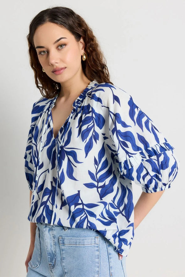 Elevate your style with our Luminary Blue Leaves Top. Featuring a quirky blue leaf print and a playful tie detail at the v neckline, this top adds a touch of fun to your wardrobe. The soft, lightweight cotton material provides comfort for everyday wear. (Fun fact: it also has half sleeves for extra coverage!)