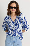 Elevate your style with our Luminary Blue Leaves Top. Featuring a quirky blue leaf print and a playful tie detail at the v neckline, this top adds a touch of fun to your wardrobe. The soft, lightweight cotton material provides comfort for everyday wear. (Fun fact: it also has half sleeves for extra coverage!)