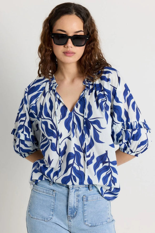 Elevate your style with our Luminary Blue Leaves Top. Featuring a quirky blue leaf print and a playful tie detail at the v neckline, this top adds a touch of fun to your wardrobe. The soft, lightweight cotton material provides comfort for everyday wear. (Fun fact: it also has half sleeves for extra coverage!)