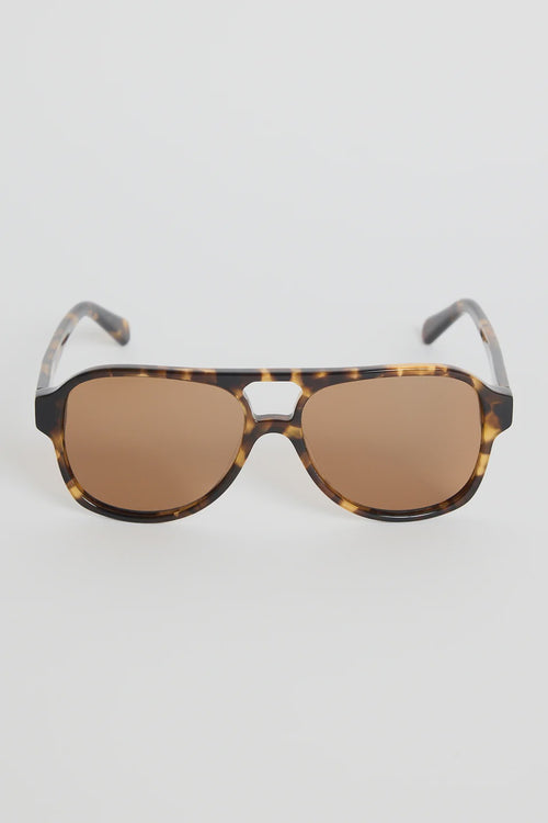 The Cannes Tort Aviator Sunglasses bring a sleek, modern twist to the classic aviator shape. Designed with a bold tortoiseshell frame and softly rounded aviator lenses, they offer that effortless mix of statement and sophistication. Warm brown lenses keep the look cohesive and flattering, making this pair an easy go-to for sunny days, road trips, and everyday wear.

A timeless style with a chic, contemporary edge.

- Modern aviator shape
- Tortoiseshell frame
- Brown tinted lenses
- Angular top bar detail
-