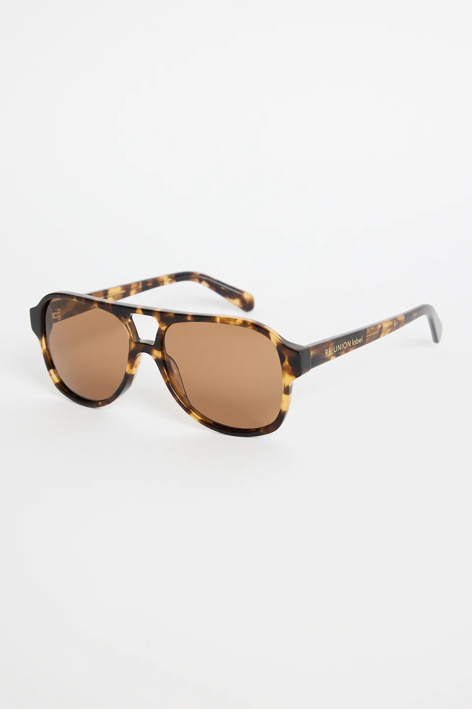 The Cannes Tort Aviator Sunglasses bring a sleek, modern twist to the classic aviator shape. Designed with a bold tortoiseshell frame and softly rounded aviator lenses, they offer that effortless mix of statement and sophistication. Warm brown lenses keep the look cohesive and flattering, making this pair an easy go-to for sunny days, road trips, and everyday wear.

A timeless style with a chic, contemporary edge.

- Modern aviator shape
- Tortoiseshell frame
- Brown tinted lenses
- Angular top bar detail
-
