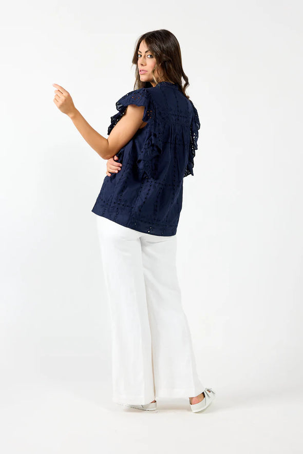 Elevate your summer wardrobe with Drama the Label's "Cards Top". This elegant top features delicate Embroidery Anglaise and a stylish Chinese Collar, along with a half-placket Button front and Sleeveless design. The cascading Frill adds a touch of grace, and the top is fully lined for comfort and quality. Pair it with Drama Shorts or Pants for a chic and sophisticated look!