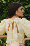 Get ready to indulge in the buttery softness of this yellow mini dress! Its playful tiered design and elastic waist provide both a comfortable fit and a feminine look. With a v neckline and drapey puff sleeves, this dress flatters your silhouette. And don't forget the charming bow and open back for added flair!