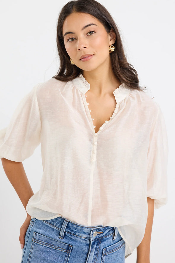 Start your day with a playful twist in the Closure Top. Featuring a high neck with charming frill details and a button front, this top also boasts mid-length balloon sleeves for added fun. Made from a semi-sheer linen blend, it offers breathable comfort that’s perfect for any occasion.