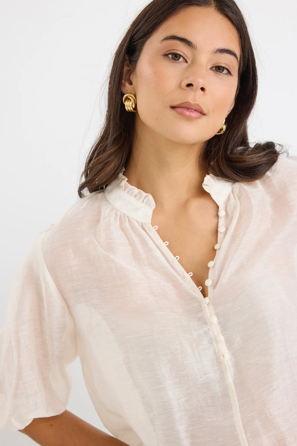 Start your day with a playful twist in the Closure Top. Featuring a high neck with charming frill details and a button front, this top also boasts mid-length balloon sleeves for added fun. Made from a semi-sheer linen blend, it offers breathable comfort that’s perfect for any occasion.