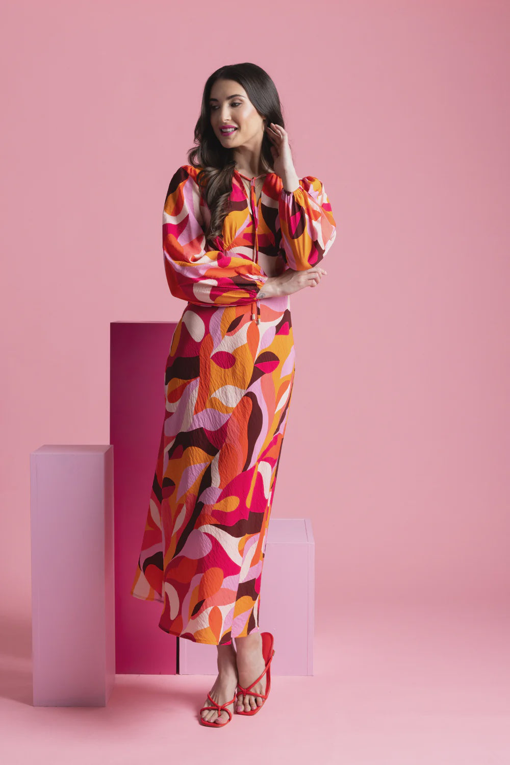 Elevate your wardrobe with our stunning long-sleeved maxi dress, crafted from a fun bright patterned fabric that effortlessly blends style and comfort. Featuring a flattering round neck with a v-neck detail and tie, this dress showcases a shaped empire bust for a feminine silhouette. The elastic cuff detail adds a touch of sophistication, while the convenient back neck zip ensures easy wear.