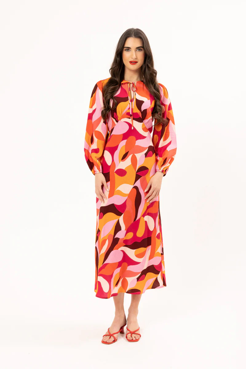 Elevate your wardrobe with our stunning long-sleeved maxi dress, crafted from a fun bright patterned fabric that effortlessly blends style and comfort. Featuring a flattering round neck with a v-neck detail and tie, this dress showcases a shaped empire bust for a feminine silhouette. The elastic cuff detail adds a touch of sophistication, while the convenient back neck zip ensures easy wear.