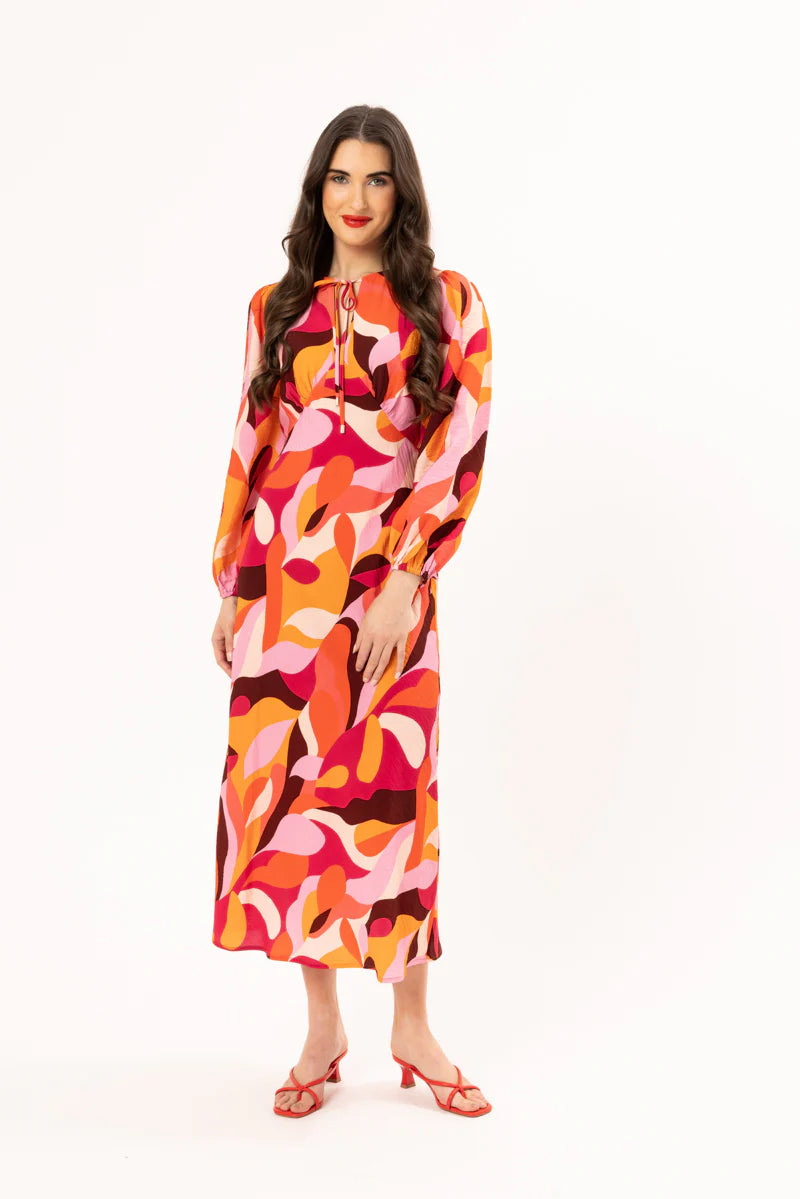 Elevate your wardrobe with our stunning long-sleeved maxi dress, crafted from a fun bright patterned fabric that effortlessly blends style and comfort. Featuring a flattering round neck with a v-neck detail and tie, this dress showcases a shaped empire bust for a feminine silhouette. The elastic cuff detail adds a touch of sophistication, while the convenient back neck zip ensures easy wear.
