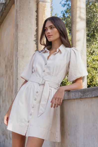 - Statement puff sleeves for a bold yet feminine look
- Button-down front for a classic touch
- Adjustable waist belt for a flattering, cinched silhouette
- Crafted from soft ecru denim with contrast stitching