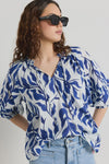 Elevate your style with our Luminary Blue Leaves Top. Featuring a quirky blue leaf print and a playful tie detail at the v neckline, this top adds a touch of fun to your wardrobe. The soft, lightweight cotton material provides comfort for everyday wear. (Fun fact: it also has half sleeves for extra coverage!)