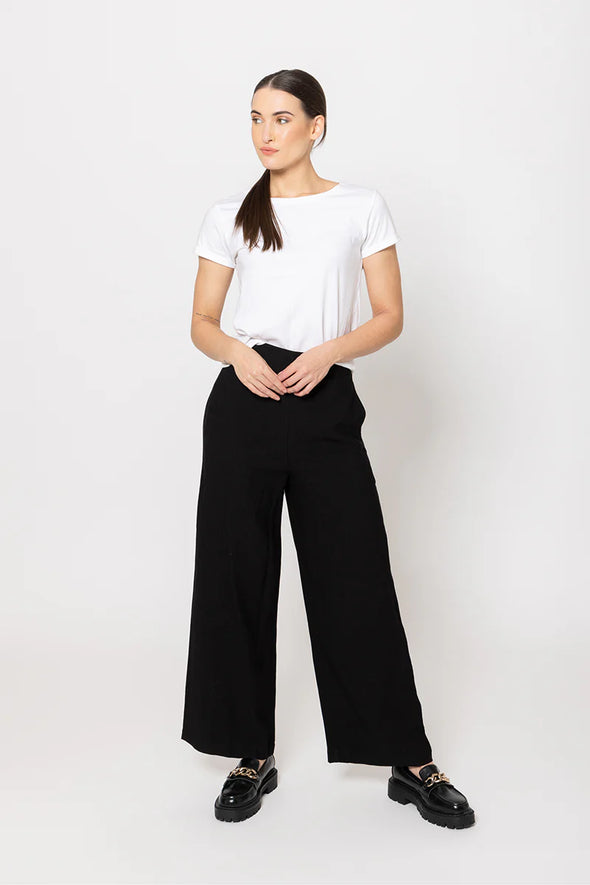Meet your new go-to: the Billie The Label Essential Wide Leg Pants in classic black. With a sleek flat front waist and comfy elastic back, they fit like a dream. Two handy pockets add practicality to the style, making them perfect for everyday adventures. Crafted from a soft blend of 65% viscose and 35% nylon, these pants offer both comfort and flow with every step.&nbsp;