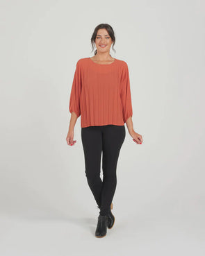 The Aura top in rust is a welcome wardrobe addition. Fantastic for layering and adds a texture element with the pleat detailing. Featuring 3/4 length batwing style sleeves with an elastic cuff and a round neckline. A great option for work or to elevate a casual look. 