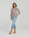 This short-sleeved shirt brings a playful touch with its softly puffed sleeves and delicate smocking that hugs the body. The gathered waist flares out into a subtle peplum, adding a flirty flair that flatters your silhouette. With refined tailoring and just the right amount of volume, it balances comfort and charm perfectly—ready to dress up your day or add fun to your casual look.