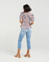 This short-sleeved shirt brings a playful touch with its softly puffed sleeves and delicate smocking that hugs the body. The gathered waist flares out into a subtle peplum, adding a flirty flair that flatters your silhouette. With refined tailoring and just the right amount of volume, it balances comfort and charm perfectly—ready to dress up your day or add fun to your casual look.