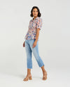 This short-sleeved shirt brings a playful touch with its softly puffed sleeves and delicate smocking that hugs the body. The gathered waist flares out into a subtle peplum, adding a flirty flair that flatters your silhouette. With refined tailoring and just the right amount of volume, it balances comfort and charm perfectly—ready to dress up your day or add fun to your casual look.
