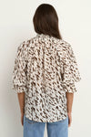 Oversized fit with flowing movement

Ruffle collar and elastic cuffs for added shape

Subtle v-neckline with easy pull-on design

Chocolate-toned animal print for a bold yet elevated look

Crafted from a breathable Tencel, linen, and nylon blend