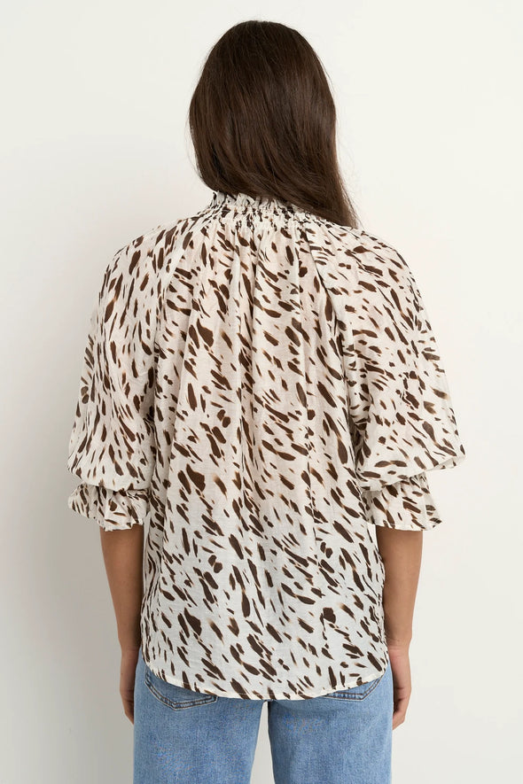 Oversized fit with flowing movement

Ruffle collar and elastic cuffs for added shape

Subtle v-neckline with easy pull-on design

Chocolate-toned animal print for a bold yet elevated look

Crafted from a breathable Tencel, linen, and nylon blend