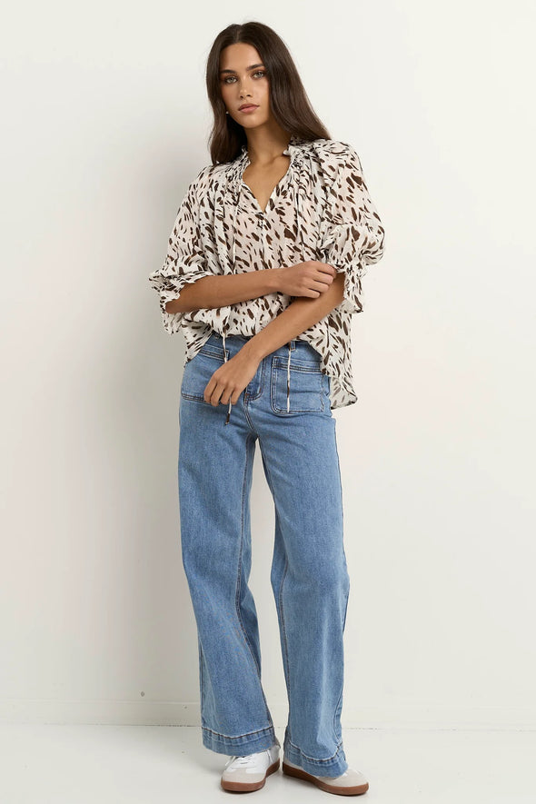 Oversized fit with flowing movement

Ruffle collar and elastic cuffs for added shape

Subtle v-neckline with easy pull-on design

Chocolate-toned animal print for a bold yet elevated look

Crafted from a breathable Tencel, linen, and nylon blend
