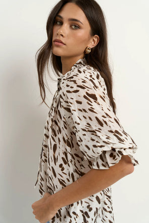 Oversized fit with flowing movement

Ruffle collar and elastic cuffs for added shape

Subtle v-neckline with easy pull-on design

Chocolate-toned animal print for a bold yet elevated look

Crafted from a breathable Tencel, linen, and nylon blend