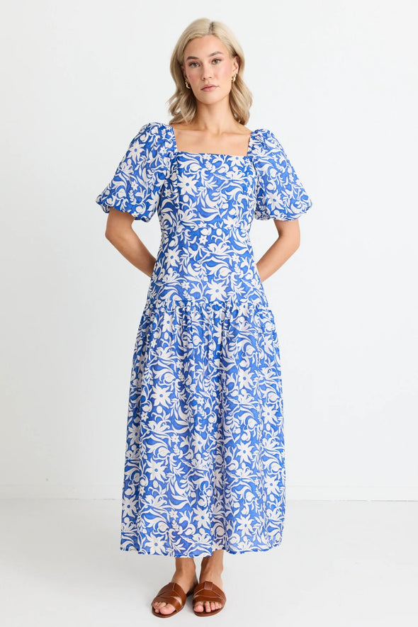 Make a statement in the Tranquillity Blue Batik Cut Out Tiered Midi Dress. With its shirred cut out back and flattering tiered design, this dress is perfect for any occasion. Elegant puff sleeves and a lightweight viscose blend add a touch of summer sophistication. Get ready to turn heads! Team up with your fav sandals for a summer outfit or add a heel for that special event.