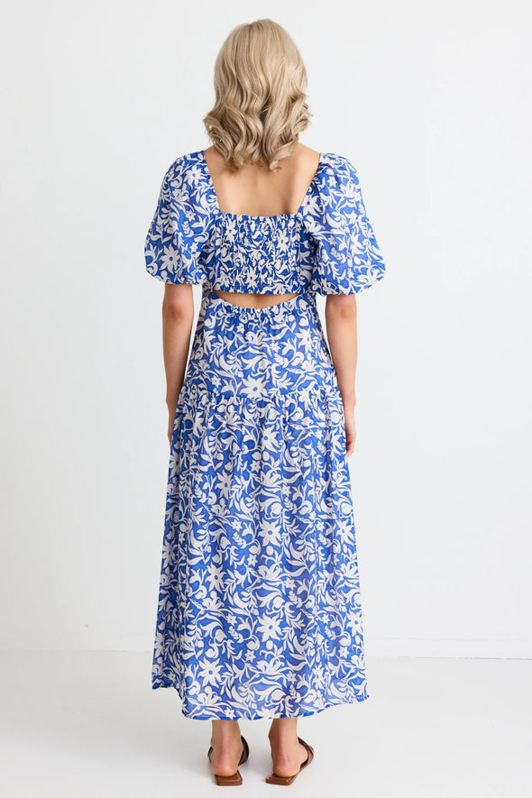 Make a statement in the Tranquillity Blue Batik Cut Out Tiered Midi Dress. With its shirred cut out back and flattering tiered design, this dress is perfect for any occasion. Elegant puff sleeves and a lightweight viscose blend add a touch of summer sophistication. Get ready to turn heads! Team up with your fav sandals for a summer outfit or add a heel for that special event.