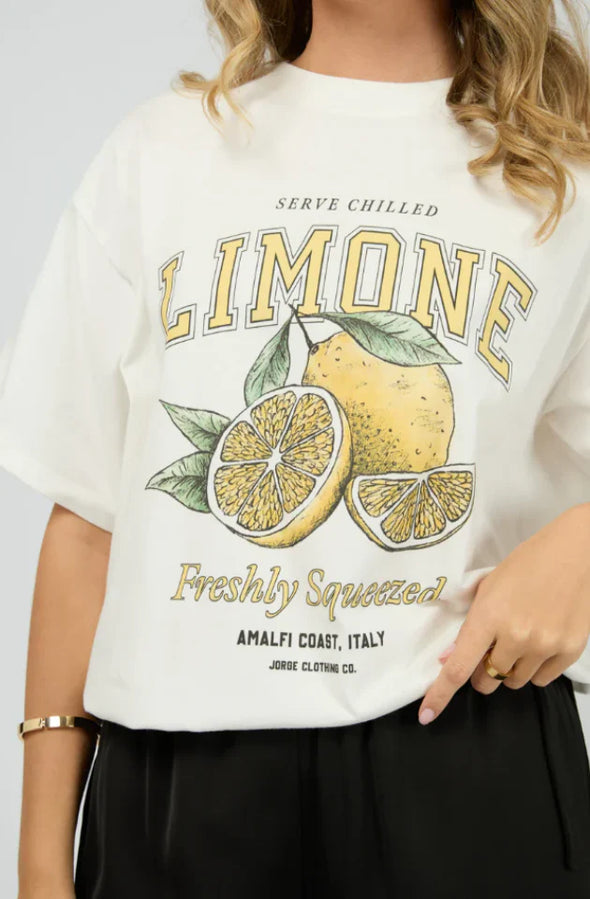 Brighten your day with the Jorge Limone Tee in Vintage White! This cool, relaxed tee features a classic crew neckline and playful vintage-style lemon graphic that’s bursting with personality. Short sleeves with extended shoulders and a straight hem complete the easy oversized fit. Perfect for sunny days—team it with denim shorts for a timeless summer vibe, or mix with wide-leg trousers and sandals to step up your casual style. Made from 100% cotton, it’s as comfy as it is fun!