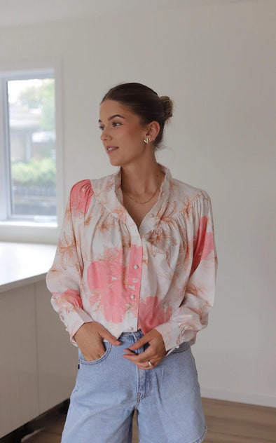 We have found the top that will be your 'nice top to go with your jeans' delicate with a white a pastel pink and natural print and feature button loops and matching fabric buttons. The shoulders have a slight lift with a gather stitch and the cuffs feature a button with split which adds to the delicate charm of this shirt.