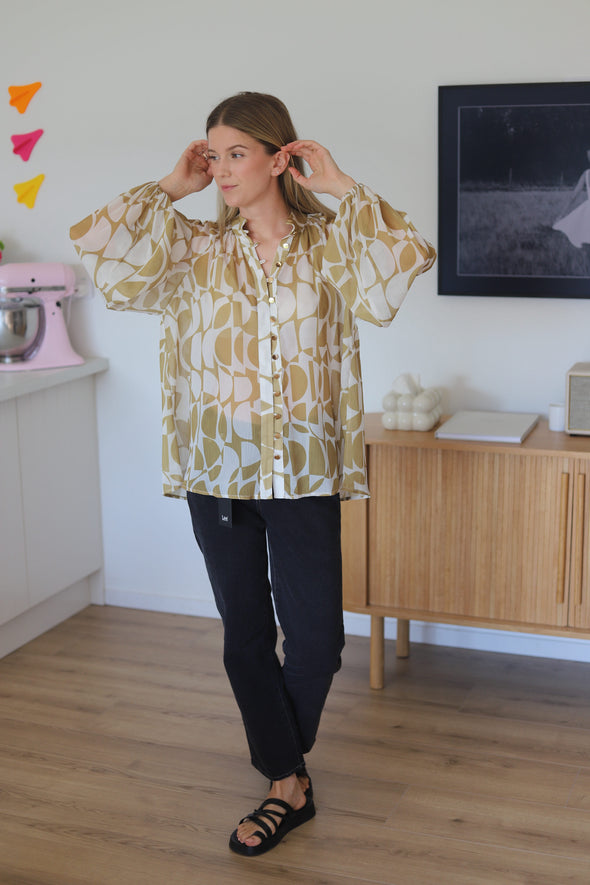 shirt featuring a stylish geometrical print in gold. The bellow sleeve detail adds a touch of elegance, and the elasticated cuffs allow you to wear them down or pushed up