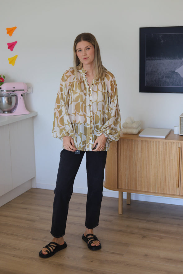 shirt featuring a stylish geometrical print in gold. The bellow sleeve detail adds a touch of elegance, and the elasticated cuffs allow you to wear them down or pushed up