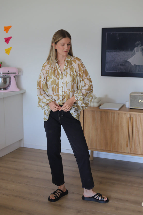 shirt featuring a stylish geometrical print in gold. The bellow sleeve detail adds a touch of elegance, and the elasticated cuffs allow you to wear them down or pushed up