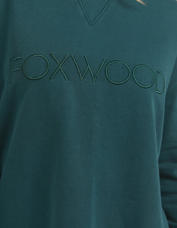 Add a pop of colour to your casual wardrobe with the Foxwood Simplified Crew in Forest Green. This vibrant crew is the ultimate layering piece, designed to bring both comfort and style to your everyday outfits. Featuring a relaxed round neckline, a flattering hi-lo hemline with side splits, and trendy raw edge detailing, this crew offers an effortlessly cool vibe. The embroidered Foxwood logo on the chest adds a touch of signature style, making this a go-to piece for any casual look.

Made from 100% cotton,