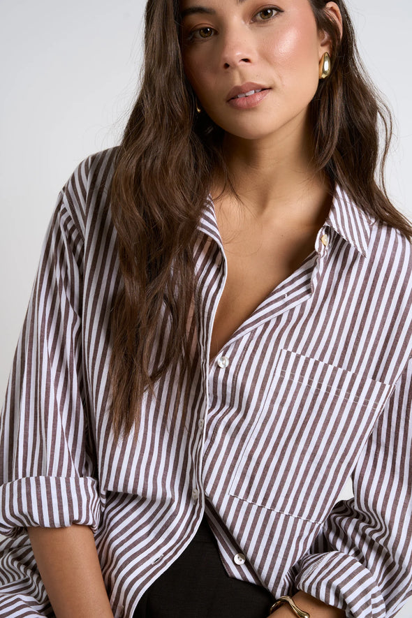 Effortlessly elevate your style with our fresh take on a classic button-up. The modern chocolate and white pinstripes add a touch of sophistication, while the lightweight fabric keeps you comfortable. Whether worn loose or tucked in, this versatile shirt is perfect for both polished office wear and casual weekends.