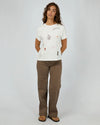 The Western Dreamer Regular Tee captures laid-back desert vibes with its crisp white fabric and playful western stamp-style prints. Its relaxed fit is perfect for tucking into denim cutoffs or layering under a slip dress, adding a subtle touch of western charm to your everyday style. Effortlessly cool and ready for any adventure!